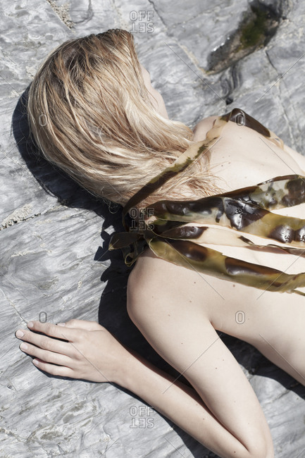 Woman lying on rock covered in kelp