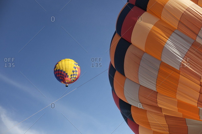 Orange hot air balloon being inflated on ground with yellow, red and blue in the air