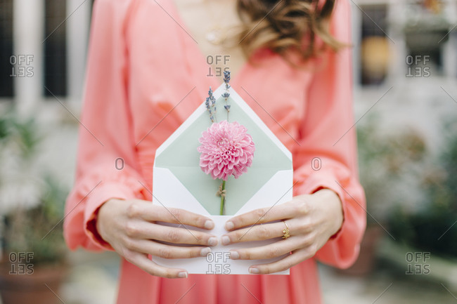 Woman with engagement ring and flower in envelope