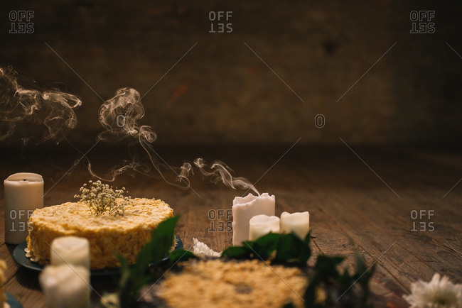 Candle smoke next to a cake covered in almonds at a dinner party