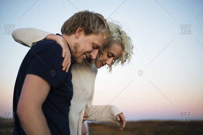Portrait of couple with arms around each other at dusk