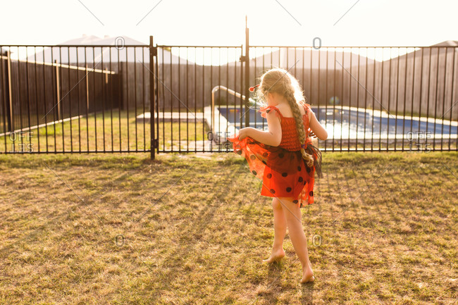 Girl in a bug costume walking toward backyard pool