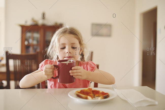 Girl enjoying warm milk and toast with jam
