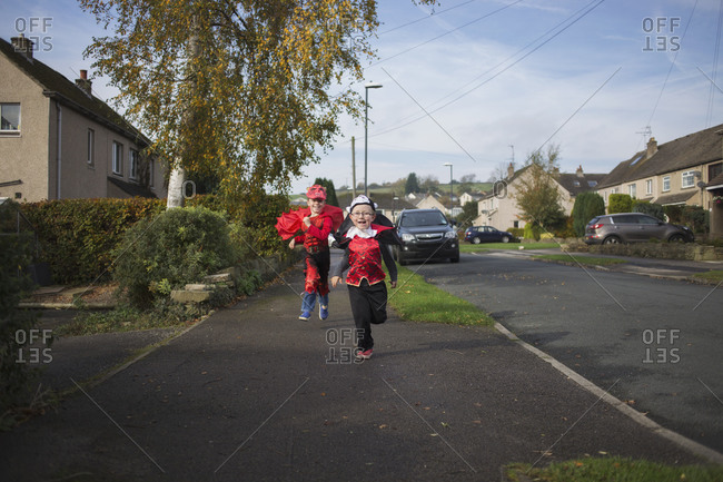 Two little boys running together in their Halloween costumes