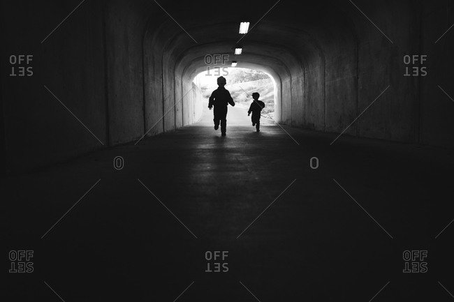 Little boys running through tunnel black and white