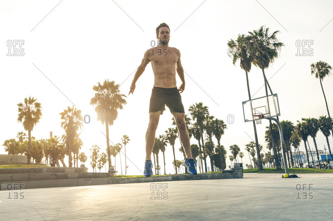 Athletic man doing workout on park basketball court