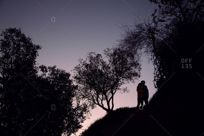 Silhouette of couple hugging on the side of a hill