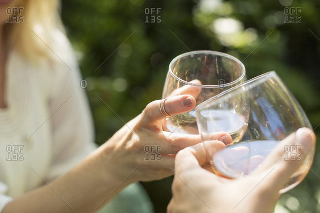 Close up of two people holding glasses with rose wine, toasting each other. Celebration.