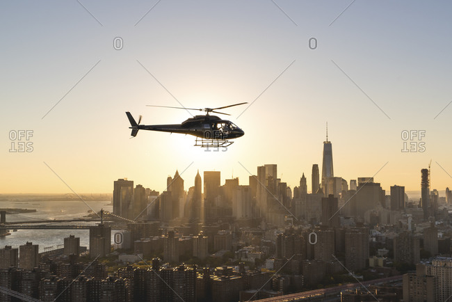 Helicopter flying above Manhattan at sunset, New York City, NY