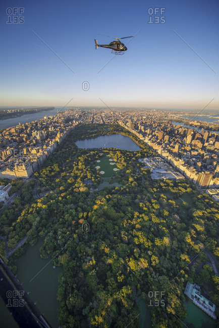 Helicopter flying over Central Park in Manhattan at sunset, New York City, NY