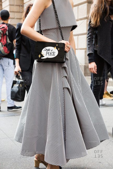 Woman in a black and white knit dress holding a bag that says \
