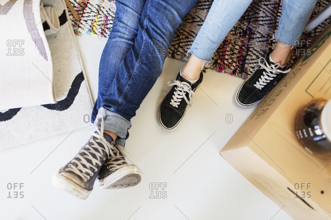 Overhead of couples feet as they rest on floor on moving day