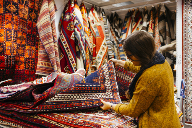 Woman browsing through selection of rugs in home goods store