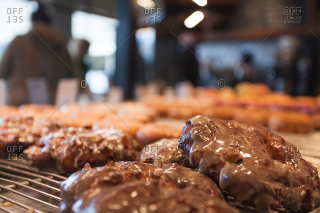 Closeup view of fresh glazed apple fritters in a donut shop