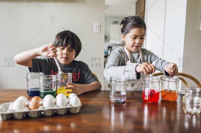 Two kids dying eggs in jars