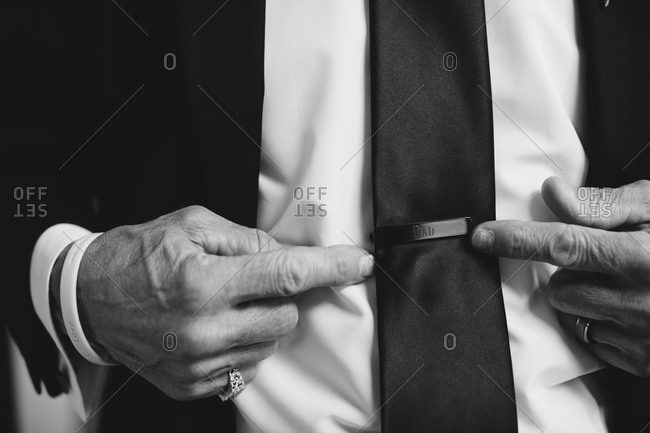 Father of the bride points to his tie clip