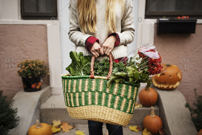 Woman with a basket full of vegetables and flowers