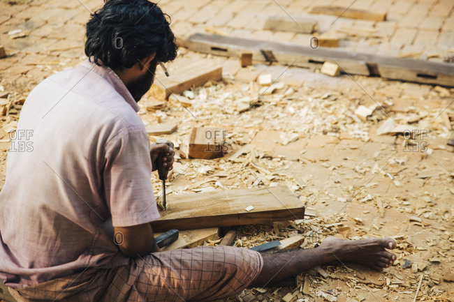 Carpenter chiseling a board in India