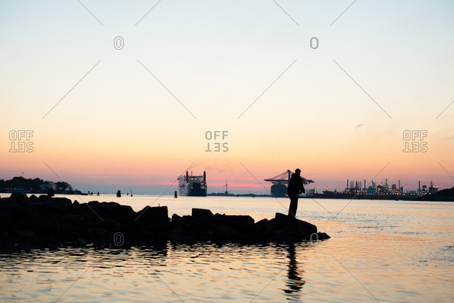 Man fishing in silhouette in Swedish harbor