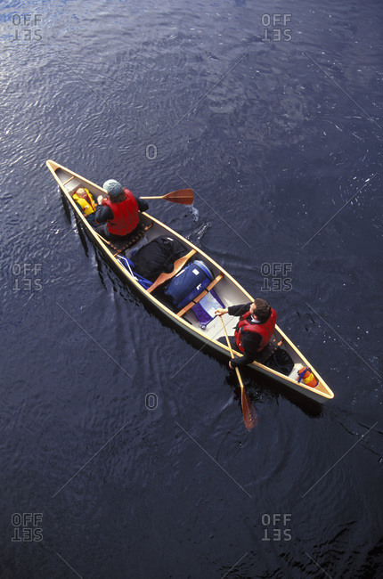 Young family paddling canoe on misty lake at sunrise near Algonquin Park, Muskoka, Ontario, Canada