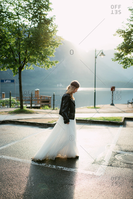 Bride walking through a parking lot beside a lake