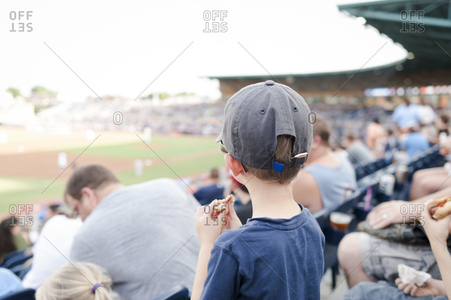 Boy eating a hotdog at a baseball game