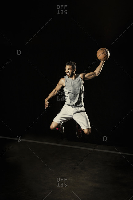 Athletic man jumping in the air with a basketball