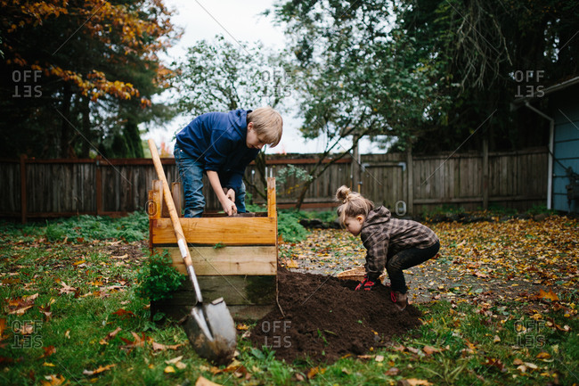 Brother and sister emptying dirt out of a small planter box