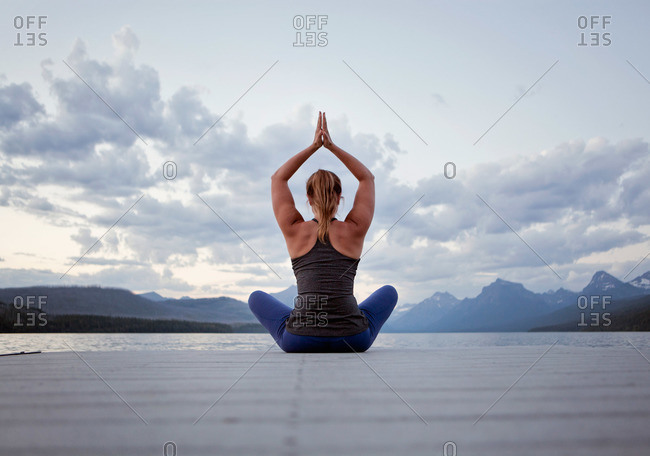 A young woman practices yoga on a dock in Montana\'s Glacier National Park