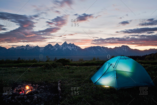 A tent and campfire glow at sunset, Tetons, Wyoming