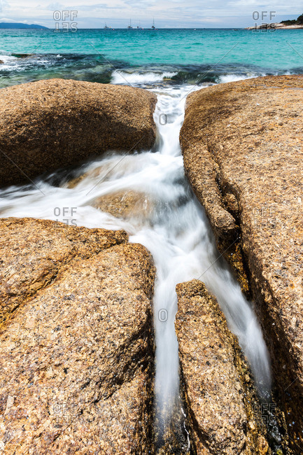 Water rushes between rocks at a Bicheno beach in Tasmania
