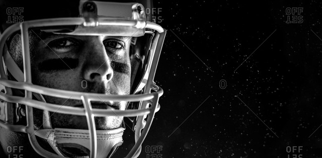 American football player looking at camera against black background