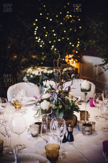 A table laid for a special occasion, with a floral centerpiece and candles, at night