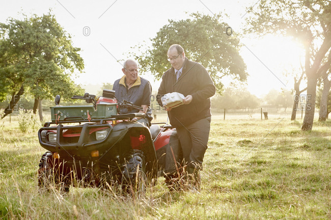 A farmer and a business manager discussing pesticides in a field