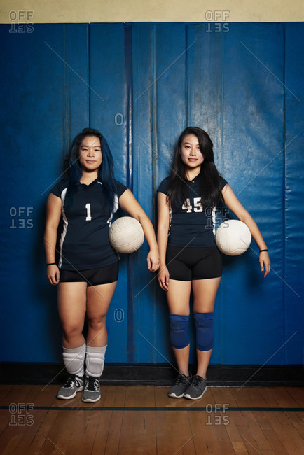 Two female volleyball players holding ball