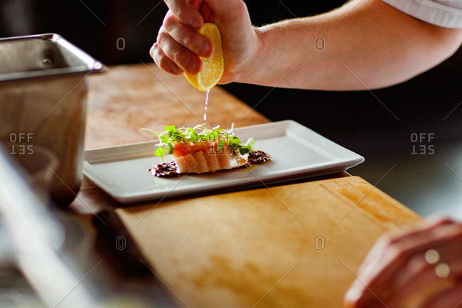 Chef squeezing lemon onto food