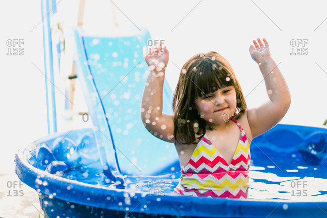 Cute young girl splashing water in kiddie pool