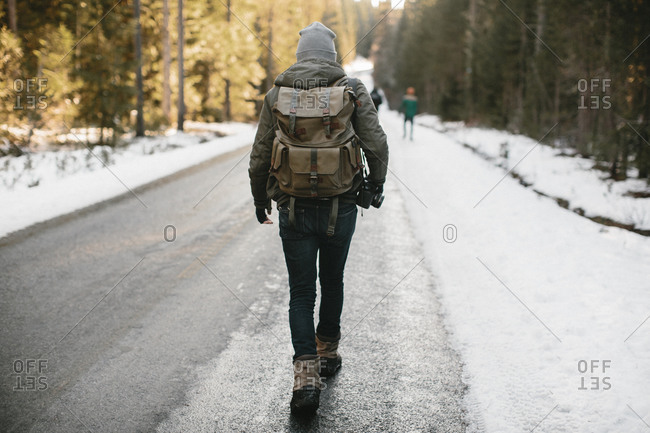 Man walking down a snowy road with a camera