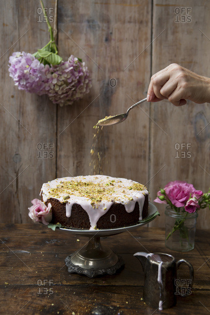 Pistachio and rose cake with hand sprinkling nuts