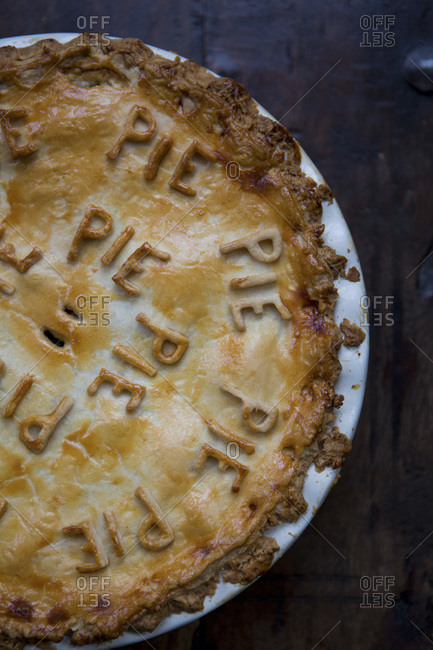 Fruit pie with pie pastry letters on dark wooden table close up