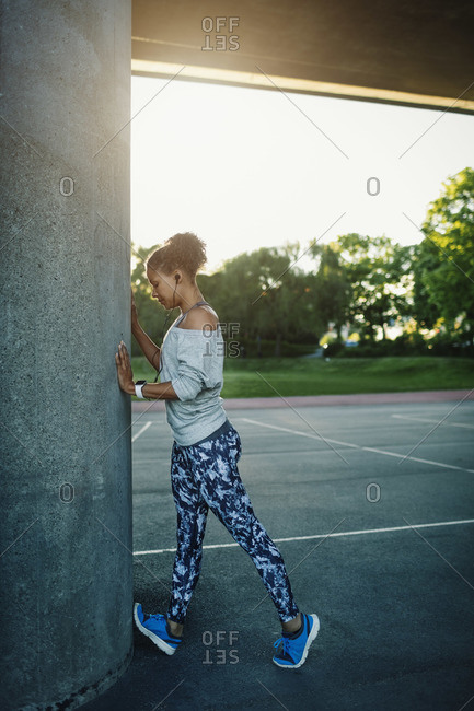 Woman stretching by column on street