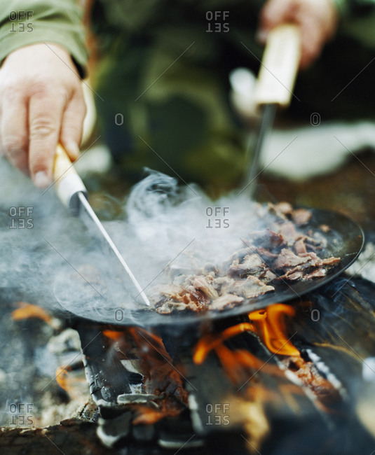Man cooking meat on a outdoor wood fire