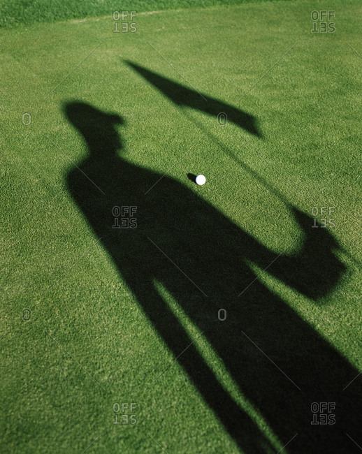 Shadow of a man holding the flag on a golf course, Sweden