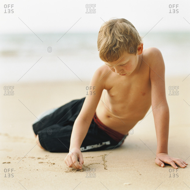 Young boy paying with sand on beach