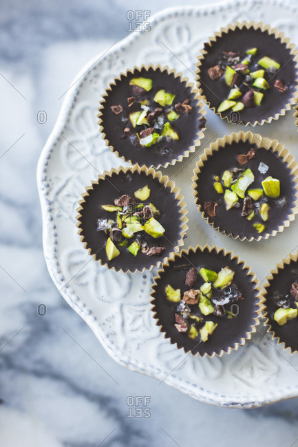 Pistachio topped chocolate cups on tray