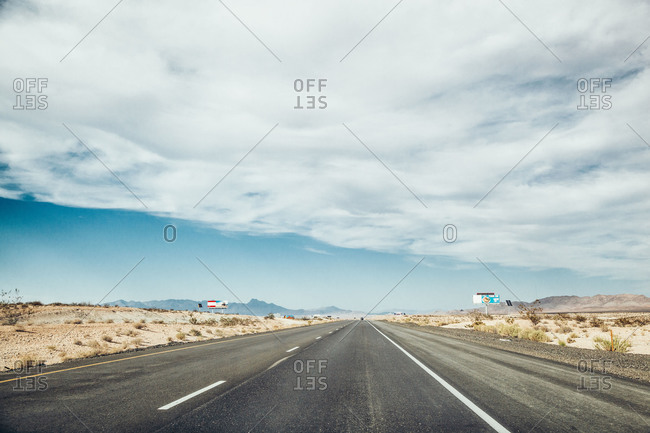 Empty desert highway under a cloudy blue sky