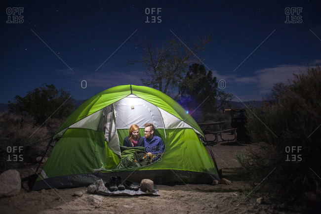 Couple sitting together in a lighted tent at night