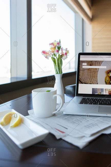 Mug of tea with lemon and laptop computer set on hotel room table