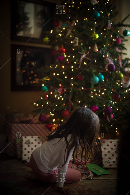 Girl looking at presents under Christmas tree