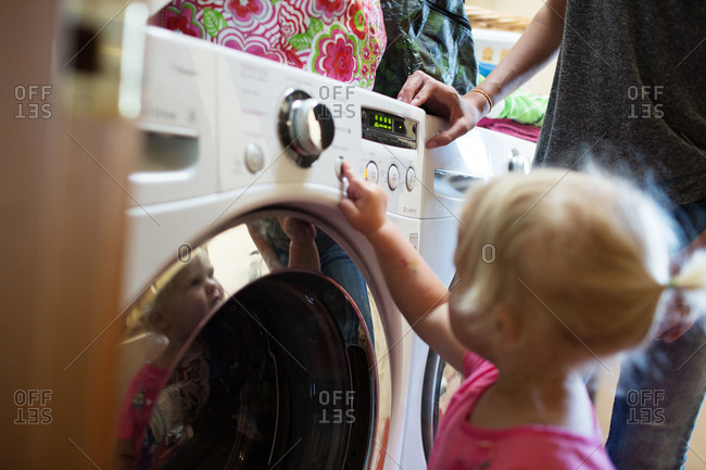 Little girl pressing buttons on washing machine
